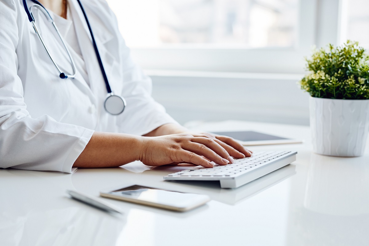 Female doctor sitting at desk typing on computer