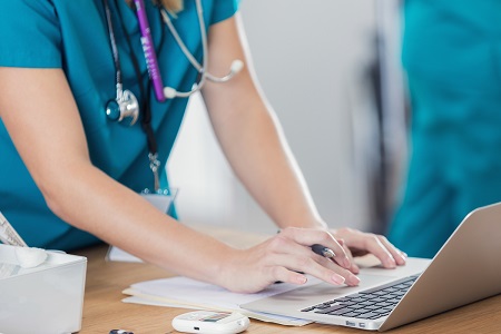 Female Nurse Typing on Laptop at Desk iStock 687660868 450